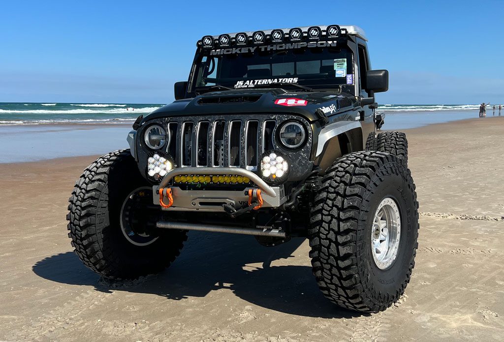 Green jeep with large tires on the beach