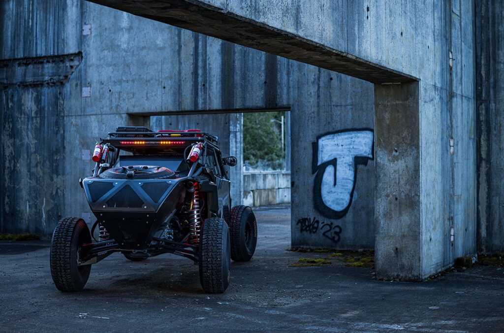 Rear view of a fully customized Can-Am Maverick X3 equipped with Baja Designs off-road LED lighting, mounted RTL rear tail light, and race-ready accessories. This high-performance UTV setup features rugged suspension, spare tire storage, and fire extinguishers, ideal for extreme off-road racing and overland adventures